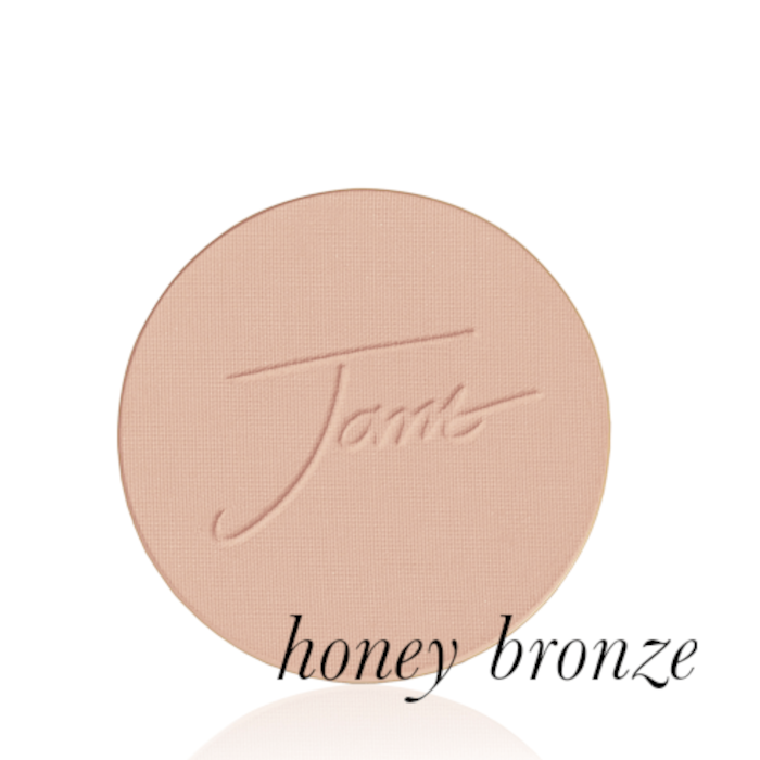 Kulatý lisovaný pudr na obličej značky Jane Iredale v odstínu Honey Bronze: středně hnědý s teplým medovým podtónem s vyraženým logem Jane Iredale.