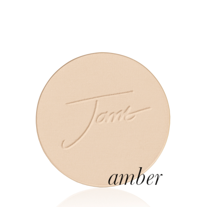 Kulatý, lisovaný pudr na obličej značky Jane Iredale v odstínu Amber, světle béžové barvy, s vyraženým logem Jane Iredale.