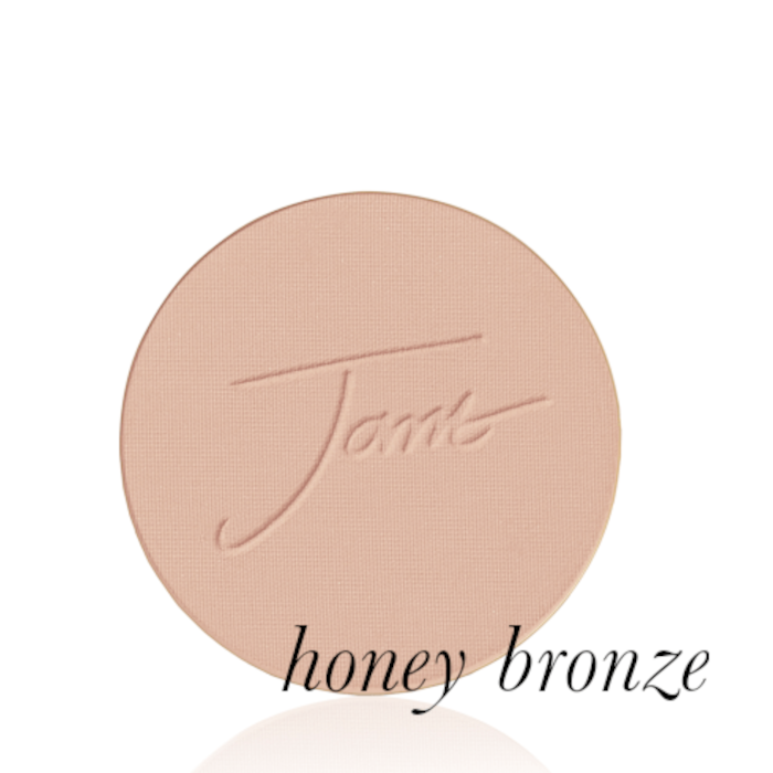 Kulatý lisovaný pudr na obličej značky Jane Iredale v odstínu Honey Bronze: středně hnědý s teplým medovým podtónem s vyraženým logem Jane Iredale.
