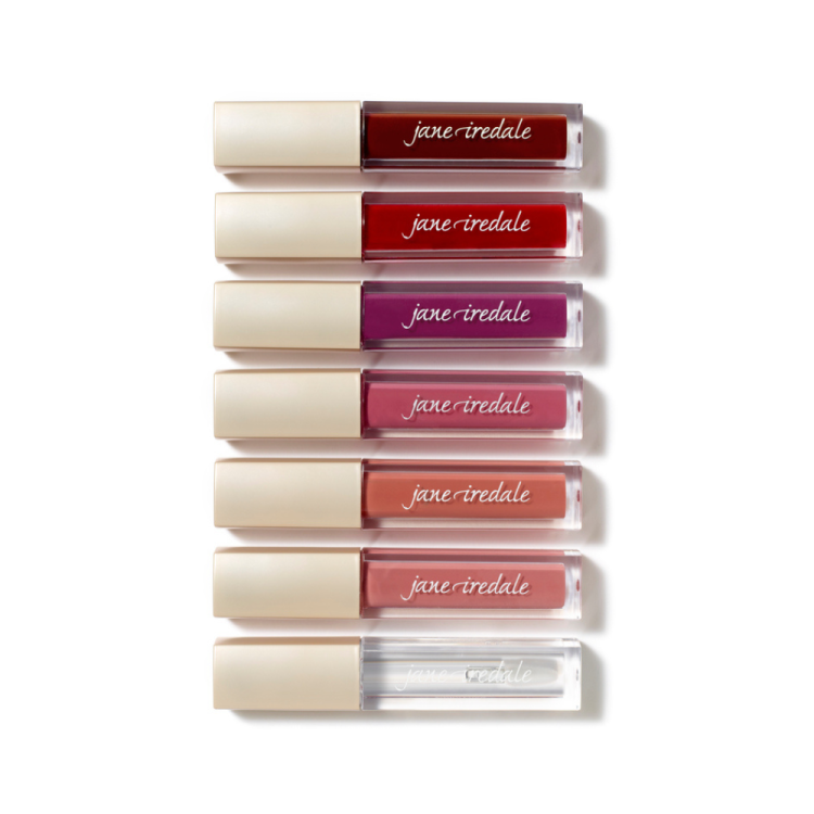 Na obrázku je sada lesků na rty Lip Glaze značky Jane Iredale. Produkty jsou uspořádány svisle nad sebou v elegantních obalech s béžovým víčkem a průhledným tělem, přes které je vidět barva lesku.