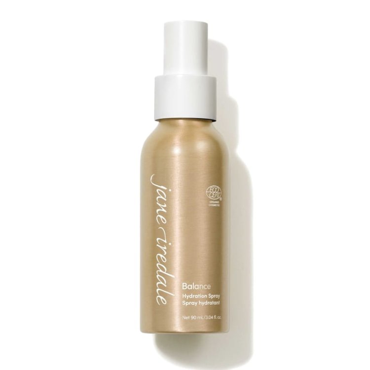 Na fotografii je elegantní zlatá lahvička s bílým rozprašovačem vody Jane Iredale Balance Hydration Spray o obsahu 90 ml. Produkt má označení ECOCERT, které potvrzuje organický a přírodní původ jeho složek.