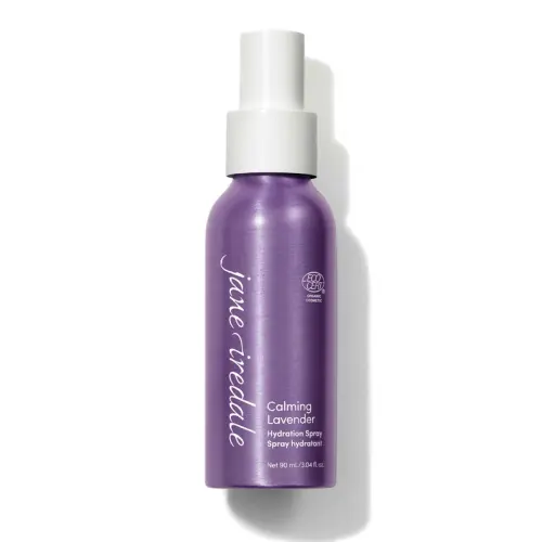 Na fotografii je elegantní fialová mini lahvička s bílým rozprašovačem Jane Iredale Lavender Hydration Spray o obsahu 90 ml. Produkt má označení ECOCERT, které potvrzuje organický a přírodní původ jeho složek.