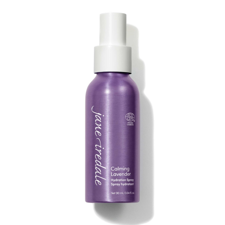 Na fotografii je elegantní fialová mini lahvička s bílým rozprašovačem Jane Iredale Lavender Hydration Spray o obsahu 90 ml. Produkt má označení ECOCERT, které potvrzuje organický a přírodní původ jeho složek.