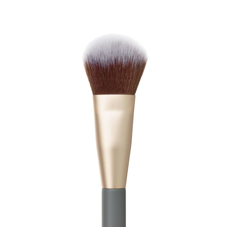 Štětec na make-up se zaoblenou, nadýchanou hlavicí. Štětiny mají jemný gradient – od světlých tónů po teplou kaštanově hnědou u kořínků. Objímka je v saténovém odstínu světlého zlata a rukojeť v matné, hluboké šedé s logem jane iredale.