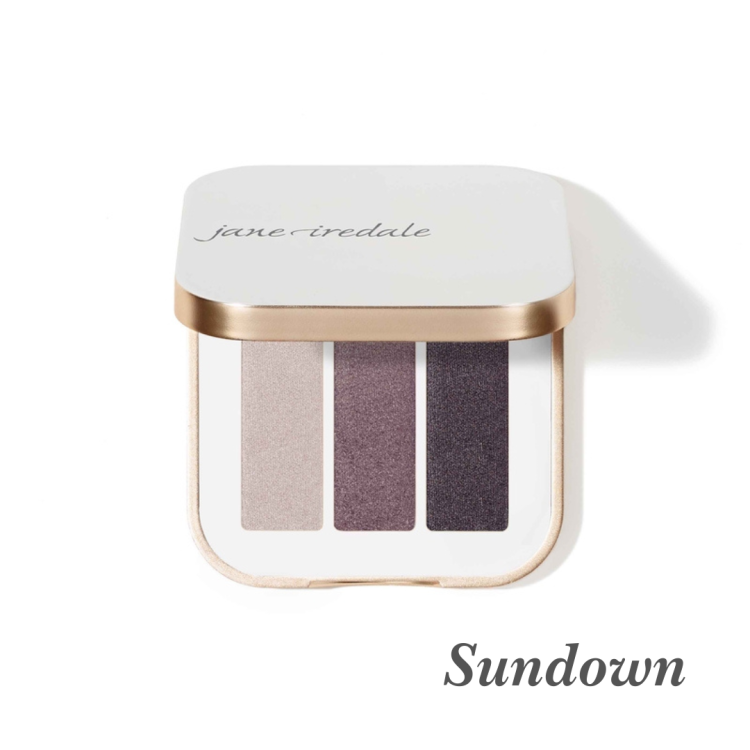 Na fotografii je trojitá paletka očních stínů Jane Iredale v odstínu Sundown. Obsahuje tři odstíny s chladnou večerní tóninou: třpytivá taupe (šedohnědá), chladná švestková s leskem, intenzivní grafitový stín s třpytem.