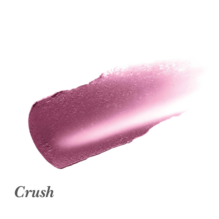 Na grafice je vidět barevná ukázka rtěnky nebo balzámu na rty značky Jane Iredale v odstínu Crush. Jde o chladnou, sytě růžovou barvu přecházející do švestkového tónu s jemným leskem. Textura působí krémově a hladce.