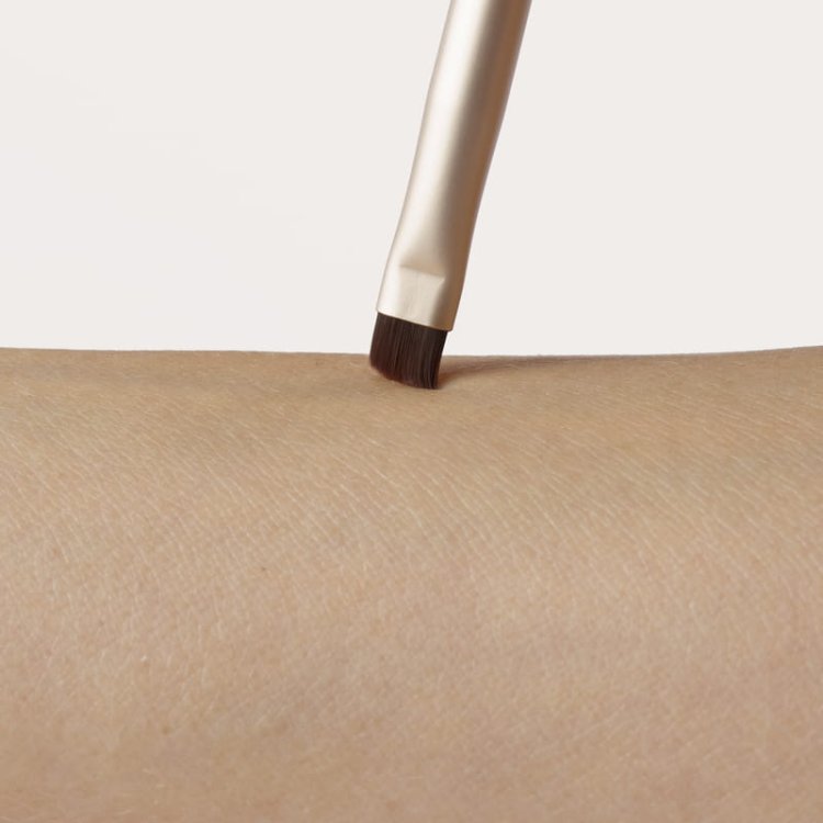 Na fotografii je šikmý štětec na make-up přikládán ke kůži. Jedná se o plochý, precizní štětec se šikmo střiženými štětinami – ideální pro aplikaci stínů a eyelinera.