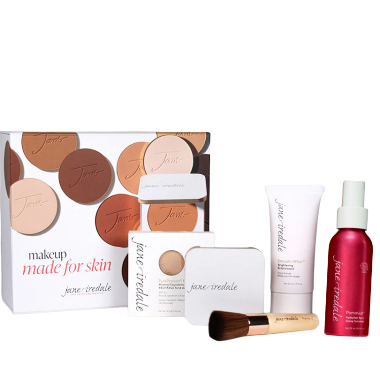 Na fotografii vidíme elegantní sadu kosmetických přípravků v otevřené bílé krabičce značky Jane Iredale. Vidíme pudr, pudřenku, sprej, podkladovou bázi a štětec Handi.