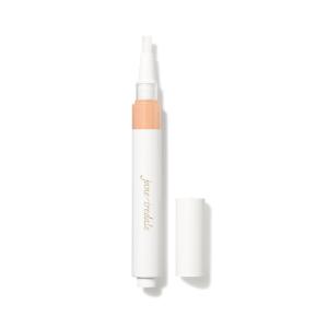 Na fotografii je korektor se štětečkovým aplikátorem značky jane iredale. Je vidět otočný obal s vestavěným aplikátorem ve formě štětečku a uzávěrem. Produkt je určen k rozjasnění očního okolí a zakrytí tmavých kruhů pod očima.