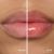 Fotografie typu „před a po“ zachycuje detail rtů modelky. Vlevo mají rty přirozenou, jemně růžovou barvu, vpravo jsou po aplikaci oleje Jane Iredale Just Kissed Lip Oil více broskvově růžové, vyhlazené a výrazně lesklé.