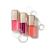 Na bílém pozadí jsou tři oleje na rty Jane Iredale Just Kissed Lip Oil v průhledných obalech s metalickými zlatými uzávěry. Oleje mají odstíny intenzivní růžové, bobulově fialové a korálové.