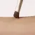 Fotografie zobrazuje detail štětce Jane Iredale Flat Eye Brush při kontaktu s pokožkou. Hustá, plochá hnědá vlákna se jemně dotýkají předloktí a ukazují tvar a preciznost hlavice štětce. Viditelná je také zlatá objímka.