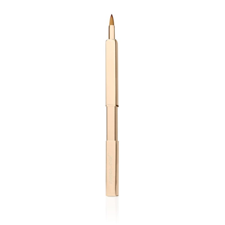Na obrázku je Retractable Lip Brush značky Jane Iredale – štětec na rty. Je zasouvací (výsuvný), hygienický a kompaktní. Obal je elegantní, zlatý, kovový, s vygravírovaným názvem značky. Štětiny jsou tenké, precizní a mají kuželovitý tvar.